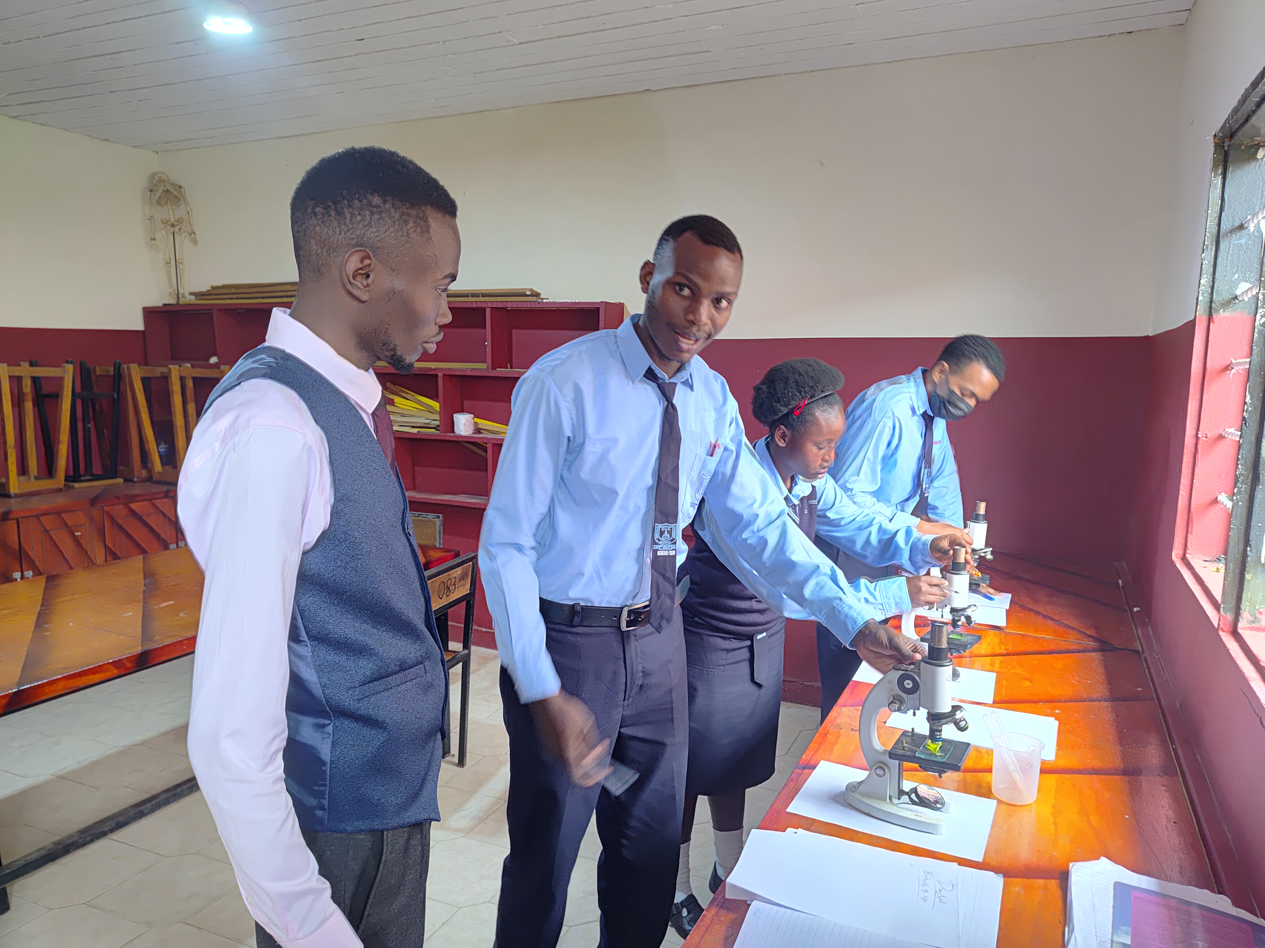 Teacher demonstrating advanced microscope techniques to students.